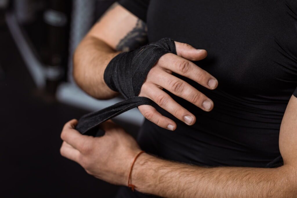 homme en train de mettre des bandes avant d'enfiler ses gants de kickboxing