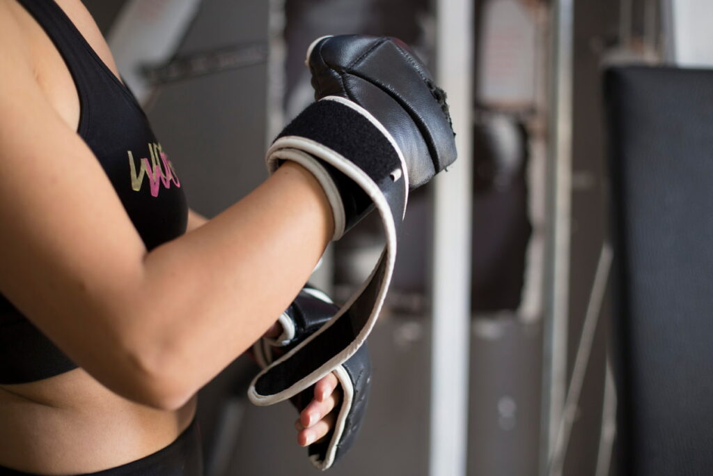 comment choisir ses gants de boxe : femme qui enfile des gants de boxe