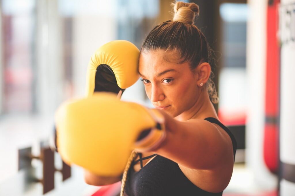 comment choisir ses gants de boxe : femme qui frappe avec des gants de boxe