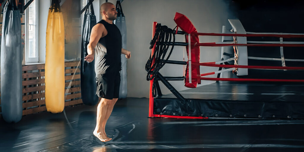 Un homme en train de faire de la corde à sauter dans une salle de boxe