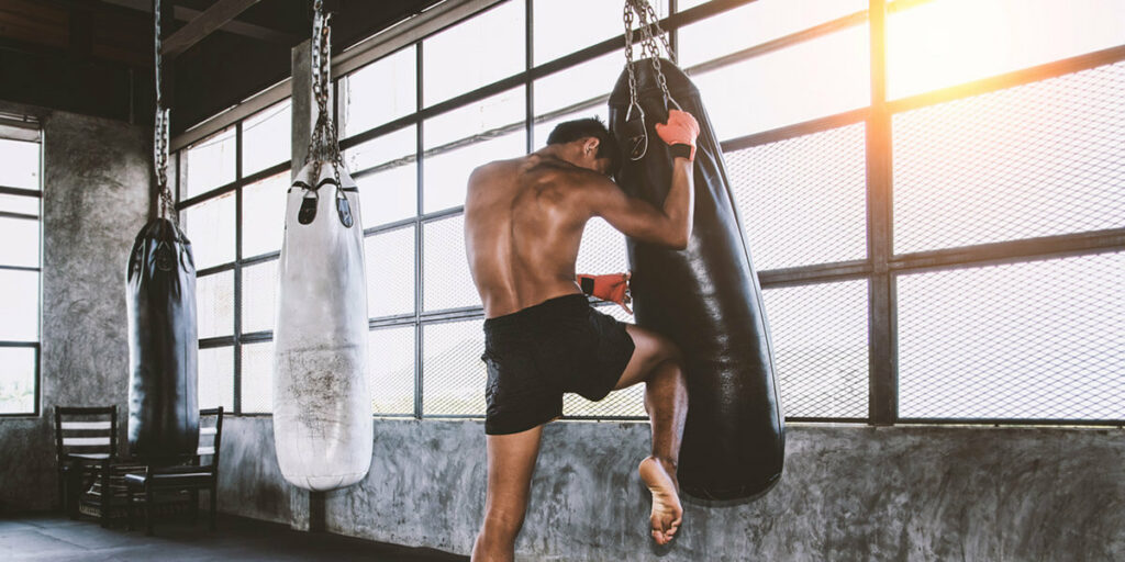 Un homme qui s'entraine à la boxe au sac de frappe