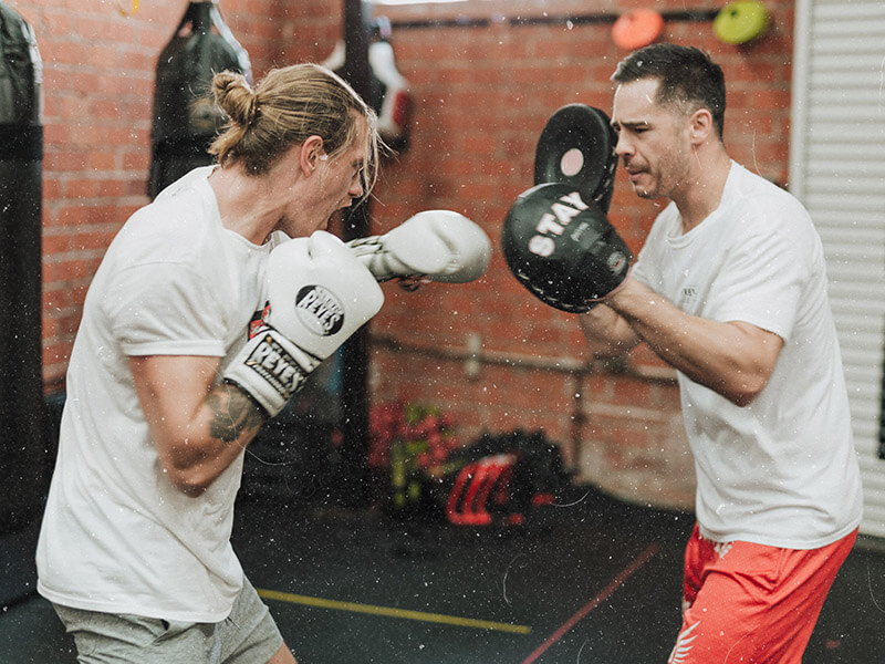 Un homme qui travaille ses punchs aux pattes d'ours pour le kick-boxing