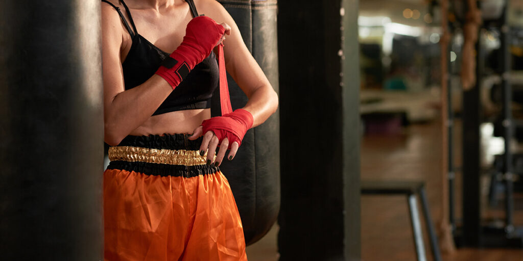 Une femme qui mets ses bandes de boxe pour son entrainement de boxe chinoise