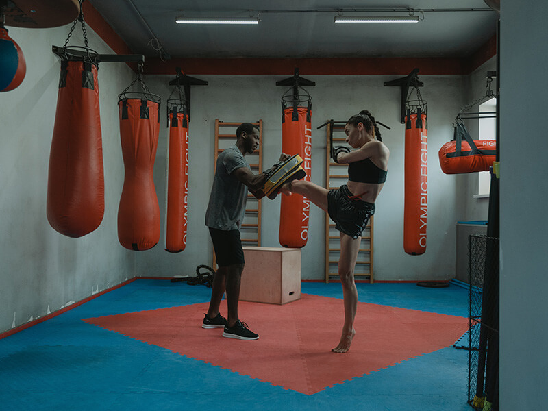 Une femme qui s'entraîne à envoyer des kicks aux paos pour la boxe chinoise