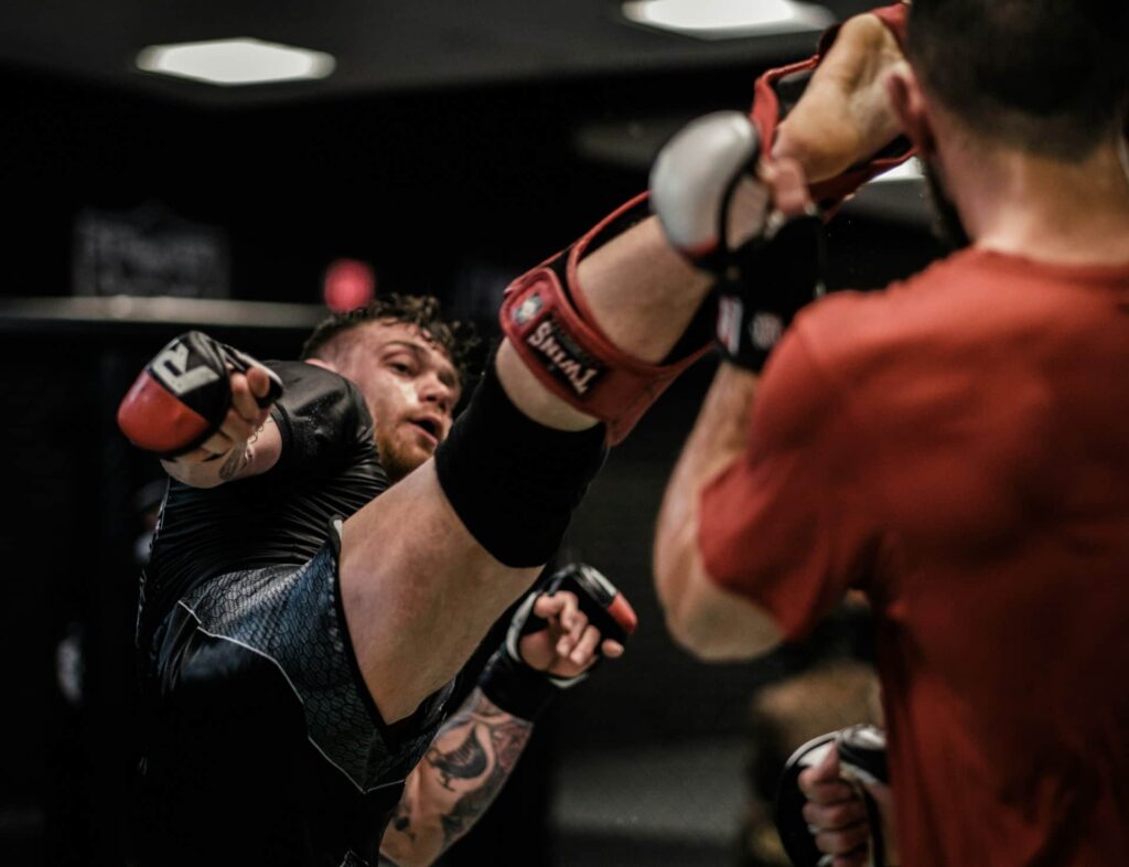 choisir protege tibia boxe : un boxeur donne un coup de pied à son adversaire
