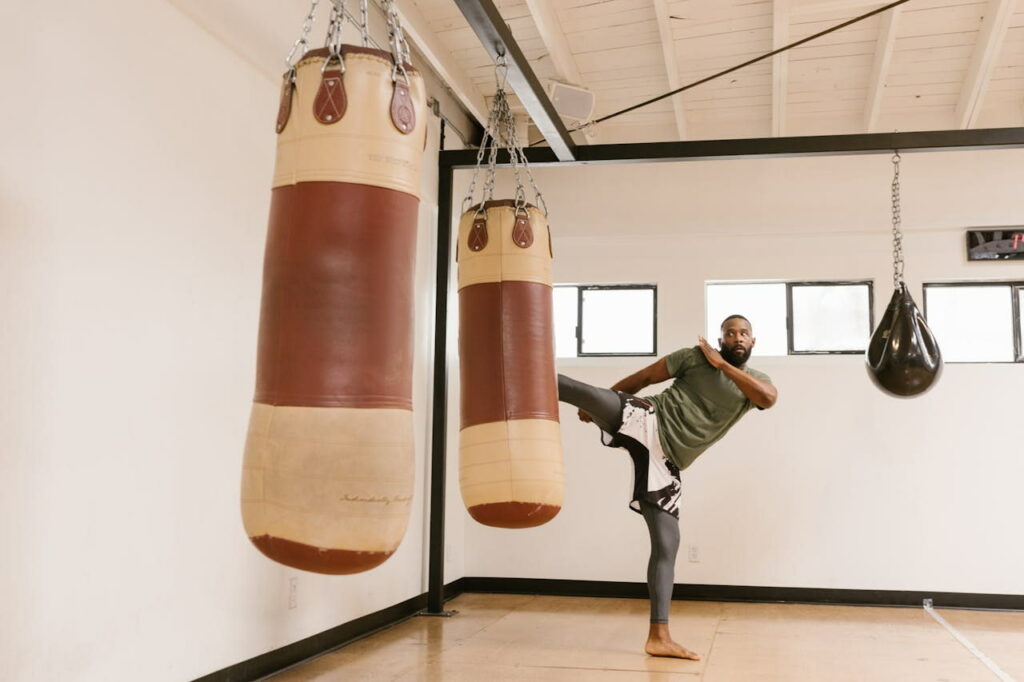 Un homme met un coup de pied dans un sac de frappe en hiit boxing