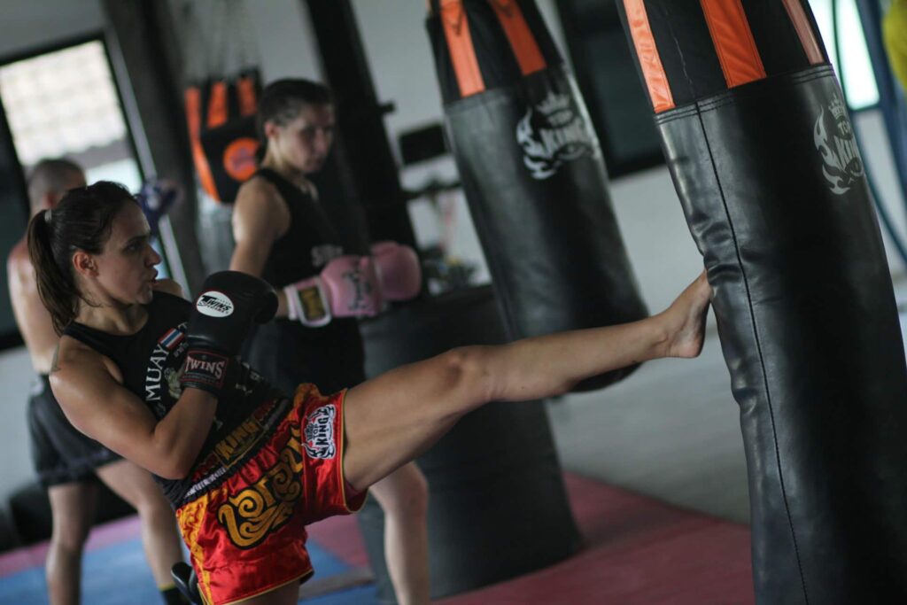 Exercice coordination boxe : une personne donne un coup de pied à un sac de frappe